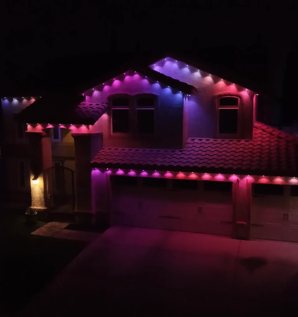 Govee Pro permanent lights in SnapTracks illuminate a two-story home's rooflines in pink, purple, and blue at night.