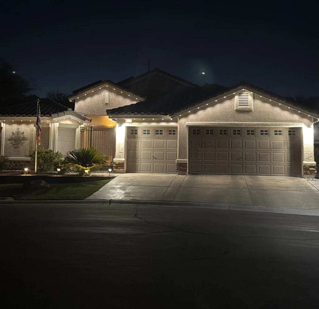 Warm-white Govee permanent lights mounted on a home's fascia boards, outlining the roofline above the garage and entryway at night.
