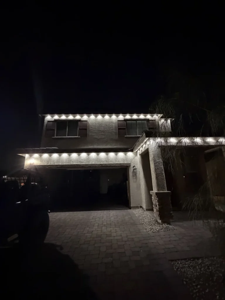 Warm white permanent roofline lights illuminating a two-story Las Vegas home at night